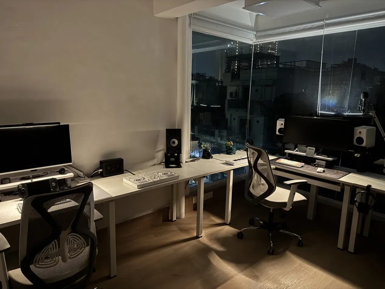 The wraparound desk after dark, city through the glass on two walls